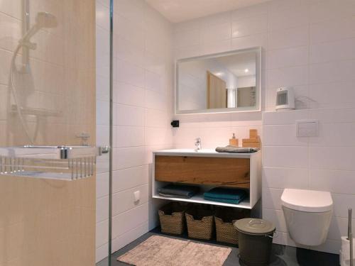 a bathroom with a sink and a toilet and a mirror at Holiday home under the trees in Labaroche