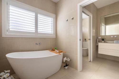 a white tub in a bathroom with a window at Sea&Country Kiama - Stunning Views-Relaxing-Spacious-Deck-EVC in Kiama