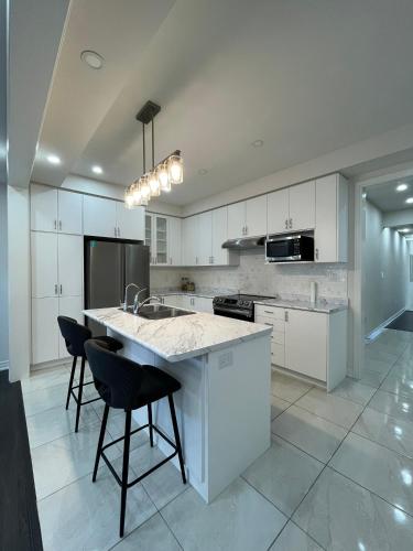 a kitchen with white cabinets and a island with chairs at Your home away from home in Hamilton