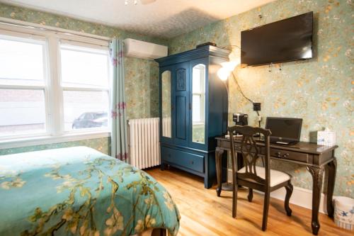 a bedroom with a bed and a desk with a computer at Prince Street Suites in Charlottetown