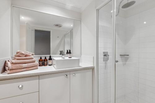 a white bathroom with a sink and a shower at Central Fremantle 2 Bedroom - Walk to Shops and Beach in Fremantle