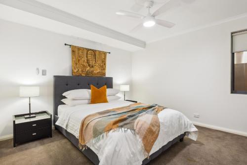 a white bedroom with a bed with orange pillows at Central Fremantle 2 Bedroom - Walk to Shops and Beach in Fremantle