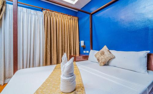 a bedroom with a white bed with blue walls at Hotel Palacio Puerto Princesa in Puerto Princesa City