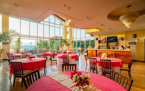 a restaurant with red tables and chairs and large windows at Hotel Palacio Puerto Princesa in Puerto Princesa City