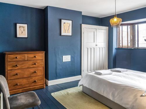 a bedroom with blue walls and a bed and a dresser at Eaton Beach House in Margate