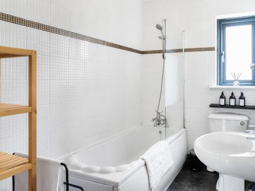 Baño blanco con bañera y lavamanos en Eaton Beach House en Margate
