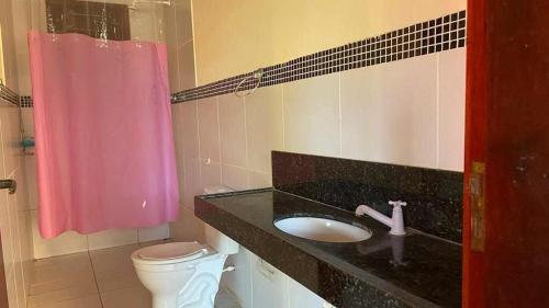uma casa de banho com um lavatório e uma cortina de chuveiro rosa em Chácara Sitio Icaraí Caucaia-CE em Caucaia