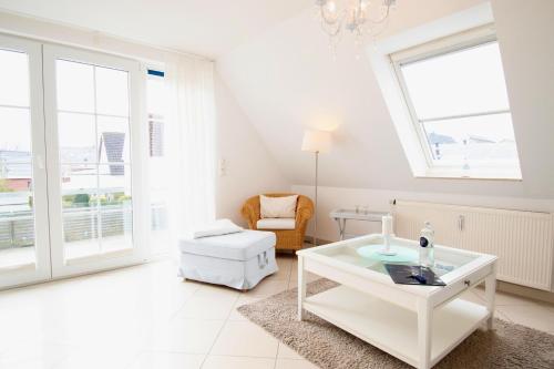 een witte woonkamer met een tafel en een stoel bij Villa Wilhelma Apartment A2 1 OG in Timmendorfer Strand