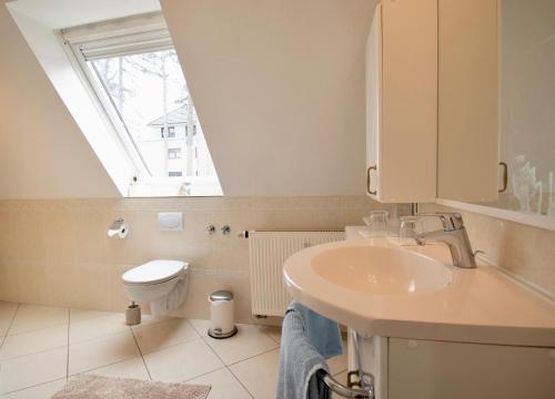 een badkamer met een wastafel en een toilet met een raam bij Villa Wilhelma Apartment A2 1 OG in Timmendorfer Strand