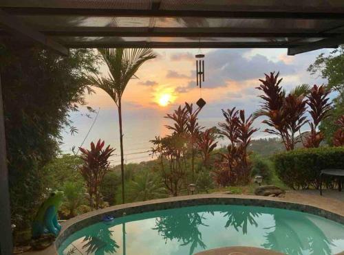 a pool in a yard with a view of the sunset at Villa Del Mar 2 Spectacular ocean view! in Dominical