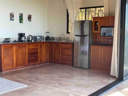 a kitchen with wooden cabinets and a stainless steel refrigerator at Villa Del Mar 2 Spectacular ocean view! in Dominical