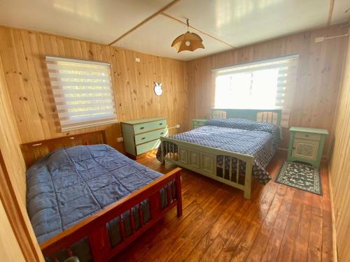 CABAÑA CON MUELLE ORILLA LAGUNA في كيلون: سريرين في غرفة نوم بجدران خشبية وأرضيات خشبية