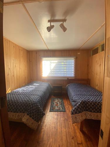 two beds in a room with a window at CABAÑA CON MUELLE ORILLA LAGUNA in Quillón