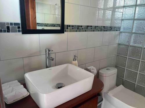 a white bathroom with a sink and a toilet at Villa Del Mar 2 Spectacular ocean view! in Dominical