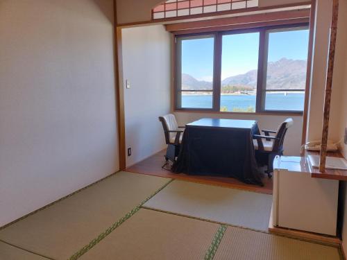 a room with a table and chairs and a window at Hotel Koryu in Fujikawaguchiko