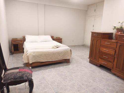 a bedroom with a bed and wooden cabinets and a chair at Apartamento/Departamento Tarija in Tarija