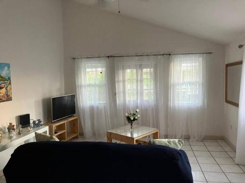 a living room with white curtains and a tv at The Residence - your home when not at home in Basseterre