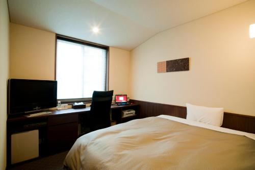 a bedroom with a bed and a desk with a computer at Ochanomizu Hotel Shoryukan in Tokyo