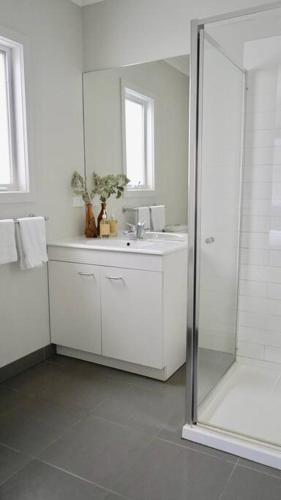 a white bathroom with a sink and a shower at Honeysuckle St Cottage. Central Location. Sleeps 8 in Bendigo