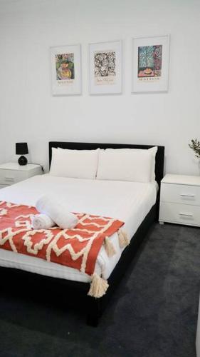 a bedroom with a bed with a red and white blanket at Honeysuckle St Cottage. Central Location. Sleeps 8 in Bendigo