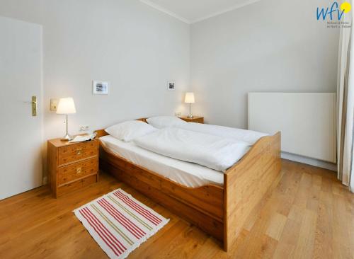 a bedroom with a large bed and a nightstand with two lamps at Haus am Hövt - Ferienwohnung 2 in Göhren