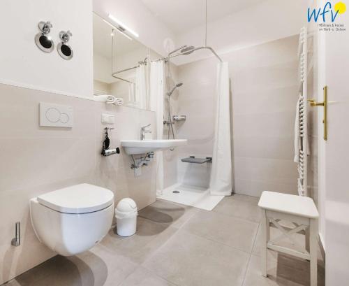 a white bathroom with a toilet and a sink at Haus am Hövt - Ferienwohnung 2 in Göhren