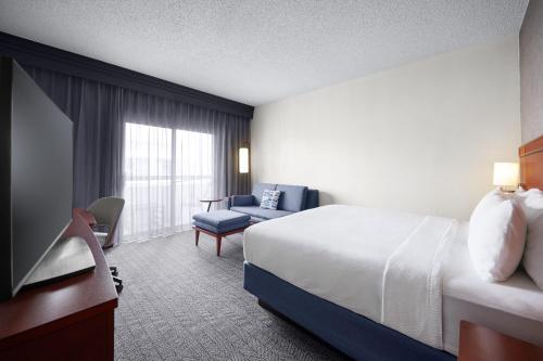 a hotel room with a bed and a chair at Courtyard Kansas City Overland Park/Metcalf, South of College Boulevard in Overland Park