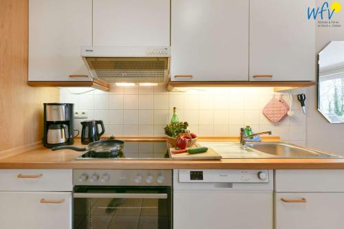 a kitchen with white cabinets and a sink at Haus am Hövt - Ferienwohnung 10 in Göhren