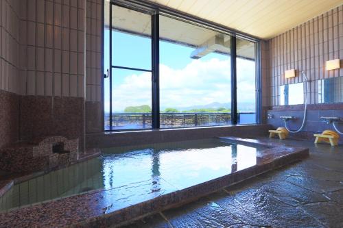 uma grande casa de banho com uma piscina de água e uma janela em 南郷温泉　二葉屋 em Otsu
