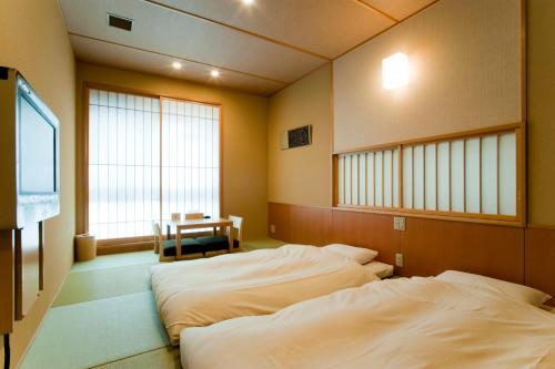 Ochanomizu Hotel Shoryukan في طوكيو: سريرين في غرفة مع تلفزيون ونوافذ