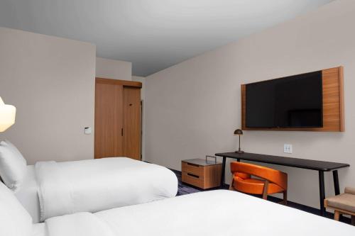 a hotel room with two beds and a desk with a television at Fairfield by Marriott Inn & Suites Lewisburg in Lewisburg