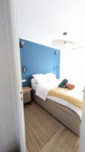 une chambre avec un lit avec une tête de lit bleue dans l'établissement L'Echo des Vagues, Appartement 2p, 50m de la plage, à Villers-sur-Mer