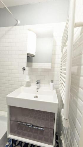 une salle de bain blanche avec un lavabo et un miroir dans l'établissement L'Echo des Vagues, Appartement 2p, 50m de la plage, à Villers-sur-Mer