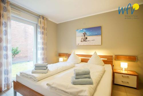 Un dormitorio con una gran cama blanca con ventana. en Ferienwohnung Weidenkieker, en Borkum