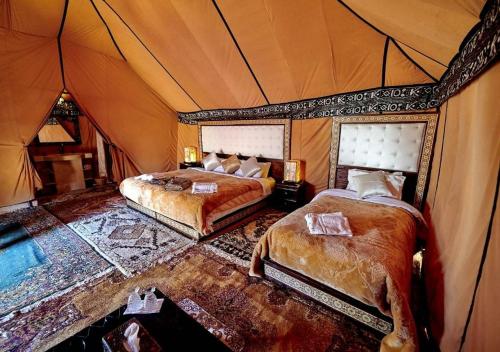 a bedroom with two beds in a tent at Shiny luxury camp in Merzouga