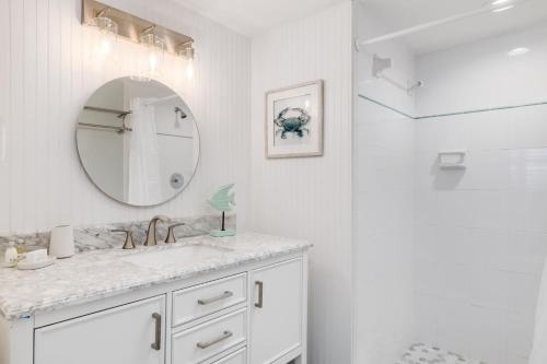 a white bathroom with a sink and a mirror at Gorgeous Top Floor Beach Condo at Breakers West in Sanibel