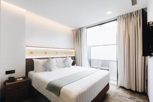 a bedroom with a large bed and a large window at Santa Grand Hotel East Coast a NuVe Group Collection in Singapore