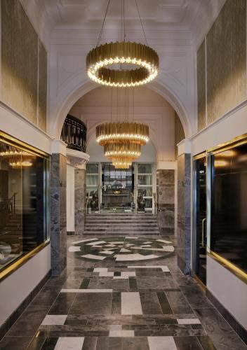 a lobby with two chandeliers and a staircase at Fable Auckland, MGallery in Auckland