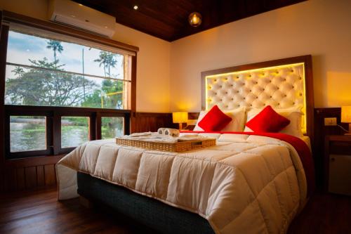 a bedroom with a large bed with red pillows at Why Not Houseboat in Alleppey