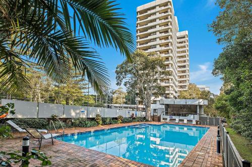 a swimming pool in front of a tall building at Pacific Towers Beach Resort in Coffs Harbour