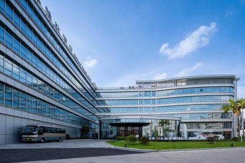 a bus parked in front of a large building at Mehood Elegant Hotel Guangzhou Baiyun Airport Huadu Cultural Tourism City in Huadong
