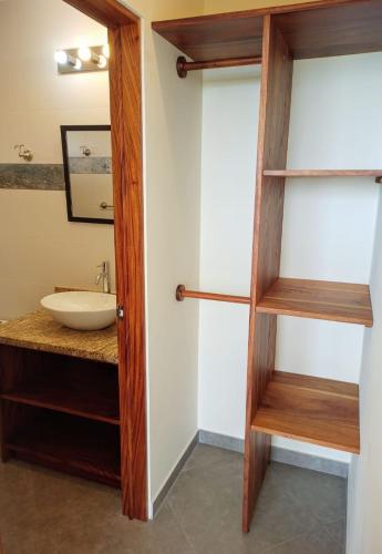 a bathroom with a wooden door and a sink at VILLA SIMONE ARENAL French Ecolodge in Tilarán