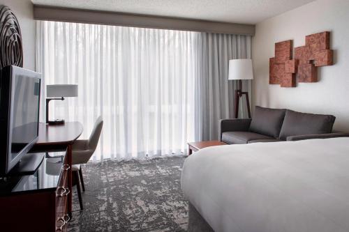 a hotel room with a bed and a couch and a television at Marriott Park Ridge in Park Ridge