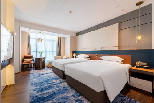 Habitación de hotel con 2 camas y sala de estar. en Mehood Elegant Hotel Guangzhou Baiyun Airport Huadu Cultural Tourism City, en Huadong