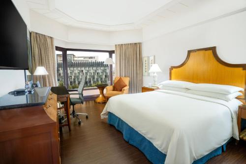 a hotel room with a large bed and a desk at Hyderabad Marriott Hotel & Convention Centre in Hyderabad