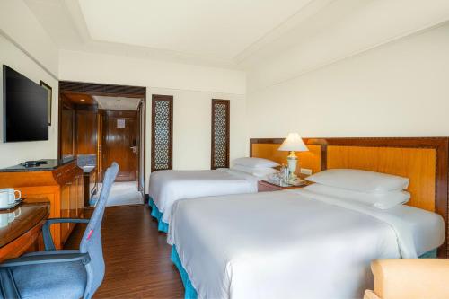 a hotel room with two beds and a television at Hyderabad Marriott Hotel & Convention Centre in Hyderabad