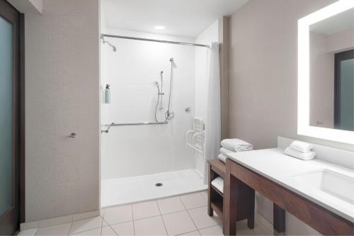 a white bathroom with a shower and a sink at Courtyard by Marriott Seattle SeaTac Airport in Seattle