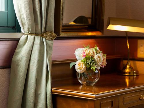 a vase of flowers on a table with a lamp at Nagasaki International Hotel in Omura