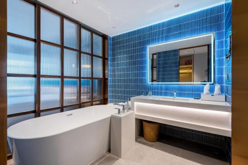baño con bañera y espejo grande en Mehood Elegant Hotel Guangzhou Baiyun Airport Huadu Cultural Tourism City en Huadong