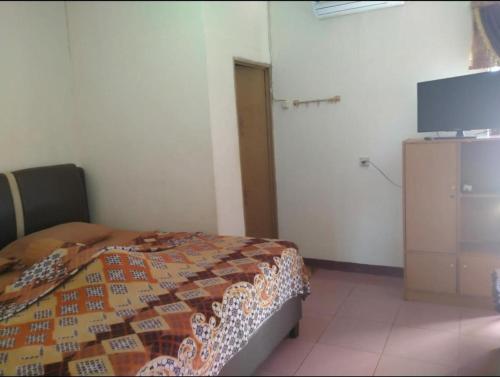 1 dormitorio con 1 cama y TV de pantalla plana en Cut Nyak Dien Guest House, en Lampung